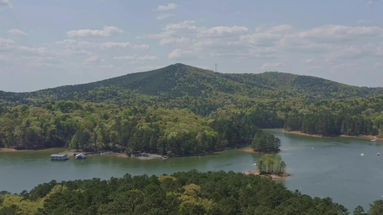 A lake curving around a wooded shoreline beneath a forested ridge.