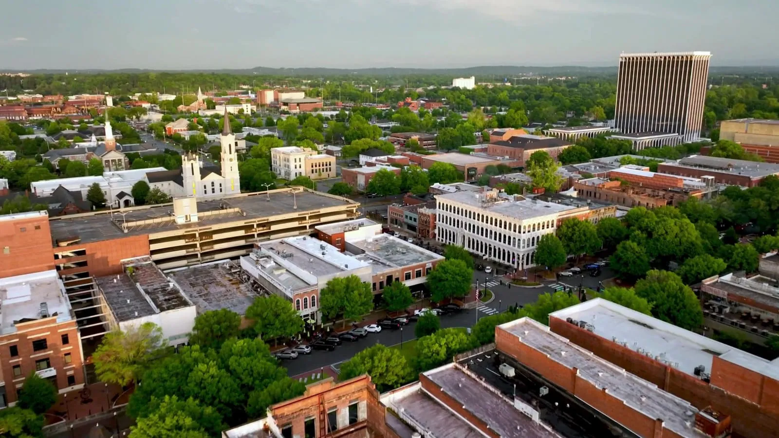 Aerial view of a historic town square and the storefronts and church steeples around it.